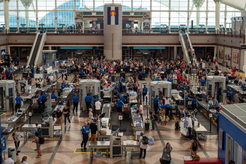TSA Workers Face Unpaid Duty: Travel Industry Prepares for Impact Busy TSA hall in Denver International Airport